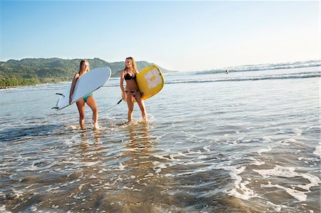 simsearch:6102-08542382,k - Two young women with surfboards wading in water Stock Photo - Premium Royalty-Free, Code: 6102-08542386