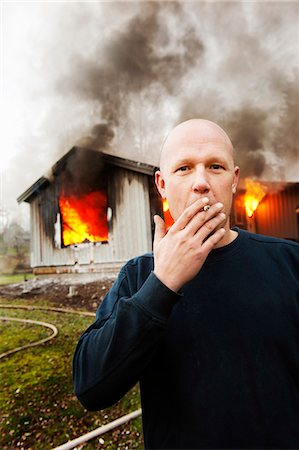 smoky - Man smoking cigarette in front of burning building Foto de stock - Sin royalties Premium, Código: 6102-08558915