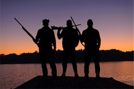 simsearch:6102-06337050,k - Silhouette of three hunters on jetty at sunset Stock Photo - Premium Royalty-Free, Code: 6102-08746263