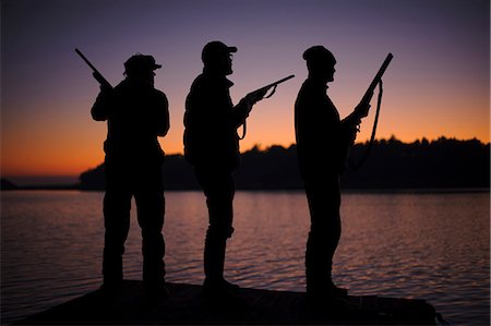simsearch:6102-06337050,k - Silhouette of three hunters on jetty at sunset Stock Photo - Premium Royalty-Free, Code: 6102-08746262