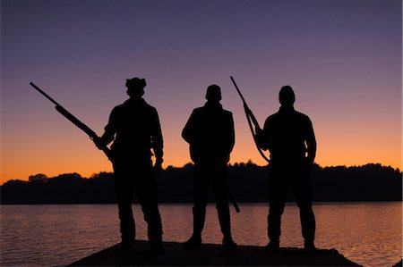 simsearch:6102-06337050,k - Silhouette of three hunters on jetty at sunset Stock Photo - Premium Royalty-Free, Code: 6102-08746264