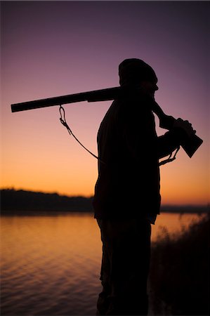simsearch:6102-06337050,k - Silhouette of hunter holding gun at lake at dusk Stock Photo - Premium Royalty-Free, Code: 6102-08746269