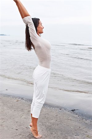 simsearch:6102-08942314,k - Young woman stretching on beach by sea Photographie de stock - Premium Libres de Droits, Code: 6102-08746905