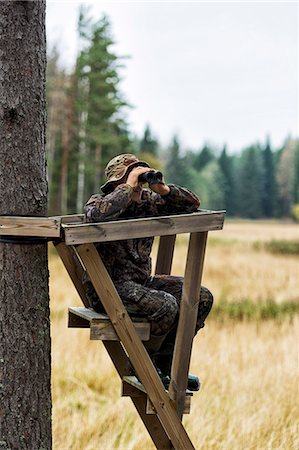 Teenager with binoculars on hunting tower Stock Photo - Premium Royalty-Free, Code: 6102-08760436