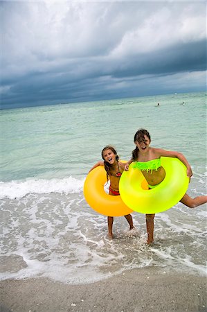 Happy girls with inflatable rings on beach Stock Photo - Premium Royalty-Free, Code: 6102-08760637