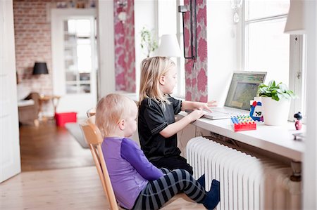 female on a radiator - Siblings using laptop in living room Photographie de stock - Premium Libres de Droits, Code: 6102-08858767