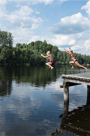 Mother jumping with son from jetty Stock Photo - Premium Royalty-Free, Code: 6102-08951279