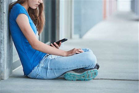 sitting in jeans - Teenager girl using cell phone Stock Photo - Premium Royalty-Free, Code: 6102-08951939