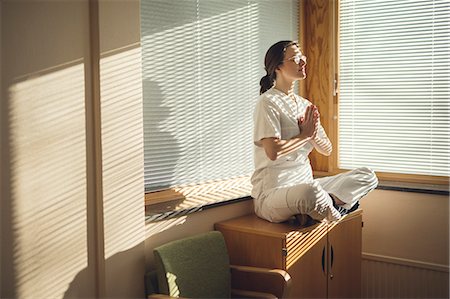 Female doctor meditating by window Stock Photo - Premium Royalty-Free, Code: 6102-08952049
