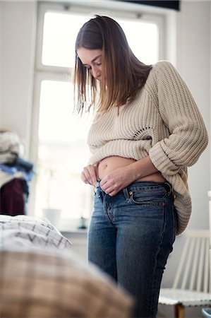 Pregnant woman getting dressed Stock Photo - Premium Royalty-Free, Code: 6102-08996663