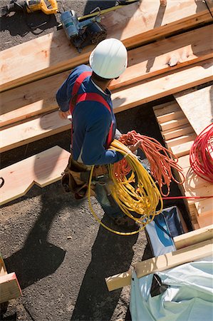 rolled up (closely coiled) - Carpenter holding coiled power cords and air hose Stock Photo - Premium Royalty-Free, Code: 6105-05396053