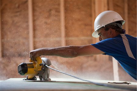 sheath - Charpentier hispanique à l'aide d'une scie circulaire sur le revêtement de toiture sur une maison en construction Photographie de stock - Premium Libres de Droits, Code: 6105-05396168