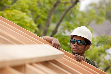 Hispanic carpenter inspecting rafters at a house under construction Stock Photo - Premium Royalty-Free, Code: 6105-05396115