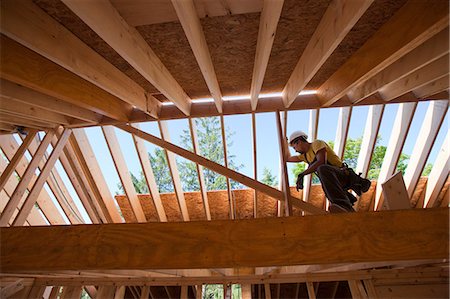 experto (hombre y mujer) - Hispanic carpenter using circular saw on rafter at a house under construction Foto de stock - Sin royalties Premium, Código: 6105-05396256