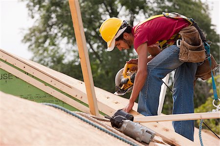 sawing - Hispanic carpenter using a circular saw on the roof at a house under construction Stock Photo - Premium Royalty-Free, Code: 6105-05396290