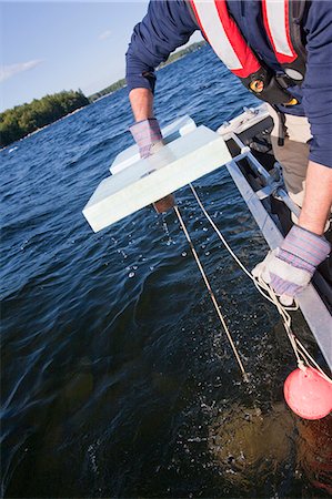Scientist pulling up a buoy attached to an algae sample Stock Photo - Premium Royalty-Free, Code: 6105-05396404
