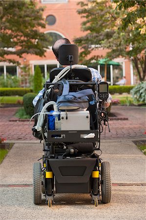 disable - Rear view of a man with Duchenne muscular dystrophy in a motorized wheelchair on the street Stock Photo - Premium Royalty-Free, Code: 6105-05396588