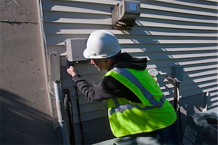 Cable engineer installing equipment on the side of a house Stock Photo - Premium Royalty-Free, Code: 6105-05396594