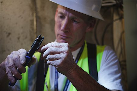 simsearch:6105-05953745,k - Cable installer putting connector on a wire in the cellar of a house Stock Photo - Premium Royalty-Free, Code: 6105-05396604