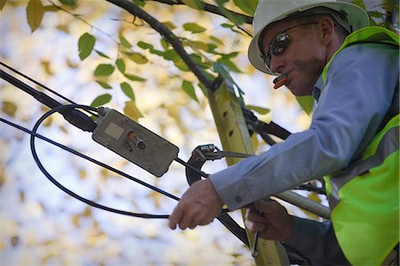 Engineer installing equipment on a power pole Stock Photo - Premium Royalty-Free, Code: 6105-05396613