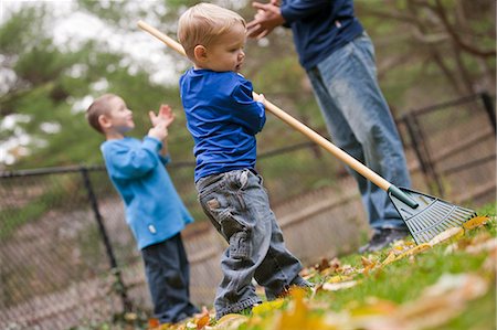 raking leaves autumn - Boy raking leaves in a park with his father and brother communicating in American Sign Language Stock Photo - Premium Royalty-Free, Code: 6105-05396773
