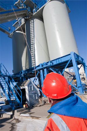 Engineer inspecting conveyor to materials silos at industrial plant Stock Photo - Premium Royalty-Free, Code: 6105-05396868