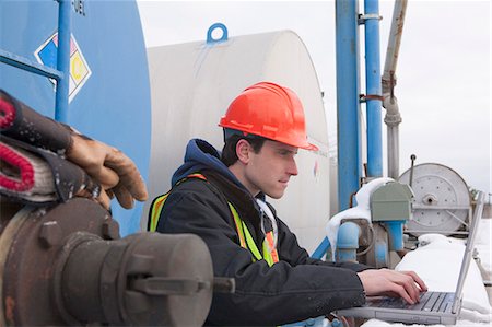 survey - Engineer recording data on a laptop near a fuel tankers site Stock Photo - Premium Royalty-Free, Code: 6105-05396980