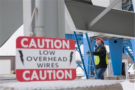 Warning sign at an industrial plant with an engineer climbing a ladder Stock Photo - Premium Royalty-Free, Code: 6105-05396988