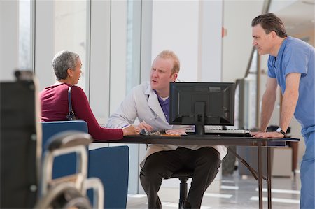 doctor standing talking to patient - Doctor and male nurse consulting with a patient Stock Photo - Premium Royalty-Free, Code: 6105-05397025