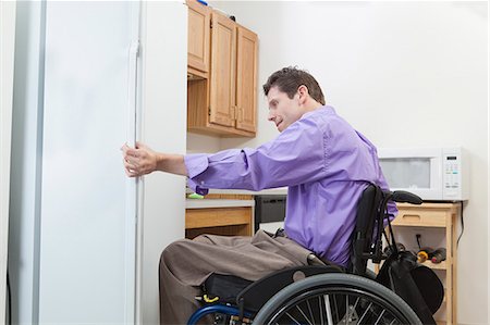 Man in wheelchair with spinal cord injury opening a refrigerator in an accessible kitchen Stock Photo - Premium Royalty-Free, Code: 6105-06042957