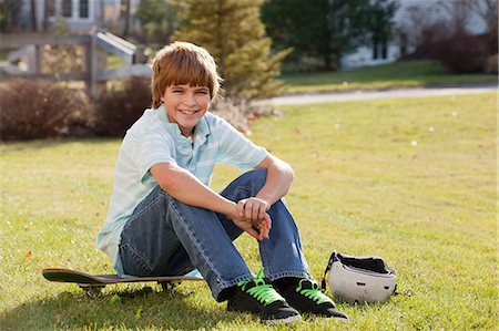 Boy sitting on his skateboard in a park Stock Photo - Premium Royalty-Free, Code: 6105-06042954