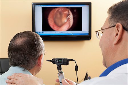 Audiologist doing live video inspection of ear canal while a patient watches on a computer screen Stock Photo - Premium Royalty-Free, Code: 6105-06042967