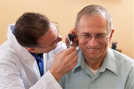 photos of us doctors - Audiologist doing an ear canal inspection Stock Photo - Premium Royalty-Free, Code: 6105-06042973