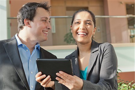 Business couple talking and smiling with a tablet Stock Photo - Premium Royalty-Free, Code: 6105-06043081