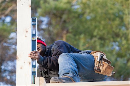 framing roof rafters - Carpenter using a level to measure vertical roof support Stock Photo - Premium Royalty-Free, Code: 6105-06043004