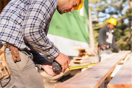 Carpenters measuring a joist in house construction Stock Photo - Premium Royalty-Free, Code: 6105-06702828