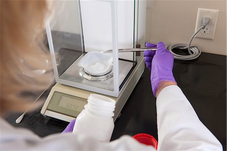 Laboratory scientist adding a small amount of solid reagent to a container on a scale Stock Photo - Premium Royalty-Free, Code: 6105-06703122