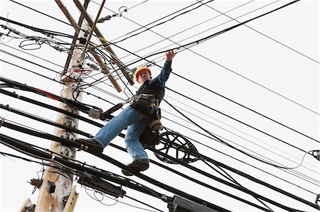 power line - Communications worker on a power pole attaching clips to support cable Stock Photo - Premium Royalty-Free, Code: 6105-07521257