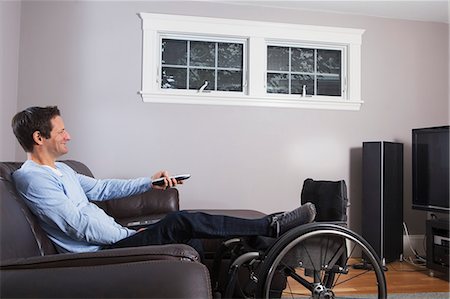 simsearch:649-07239830,k - Man with spinal cord injury with leg in wheelchair watching TV with remote Stock Photo - Premium Royalty-Free, Code: 6105-07521219