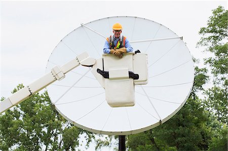 Communications engineer in bucket on truck in front of satellite dish Stock Photo - Premium Royalty-Free, Code: 6105-07521445