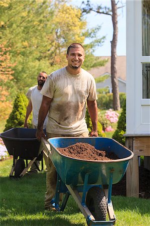 Landscapers carrying mulch to a garden in wheelbarrow Stock Photo - Premium Royalty-Free, Code: 6105-07521419