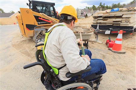 Construction supervisor with Spinal Cord Injury putting shovel into wheelbarrow Stock Photo - Premium Royalty-Free, Code: 6105-07744500