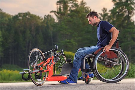 Man with spinal cord injury in his custom adaptive hand cycle getting into his wheelchair Stock Photo - Premium Royalty-Free, Code: 6105-08211279