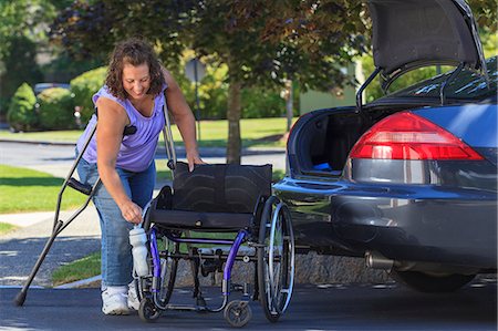 Woman with Spina Bifida taking apart wheelchair to put it in the back of car Stock Photo - Premium Royalty-Free, Code: 6105-08211297