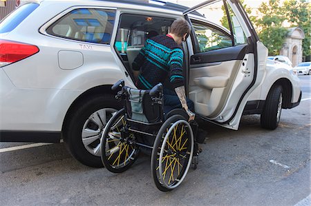 Trendy man with a spinal cord injury in wheelchair getting into a taxi cab Stock Photo - Premium Royalty-Free, Code: 6105-08211351