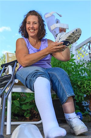 Woman with Spina Bifida adjusting leg brace so she can walk Stock Photo - Premium Royalty-Free, Code: 6105-08211306
