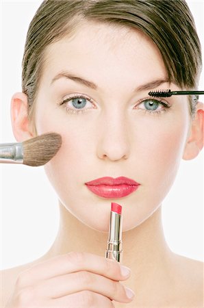 eye makeup - Visage de jeune femme avec maquillage, crayon, rouge à lèvres et un pinceau devant elle, close-up (studio) Photographie de stock - Premium Libres de Droits, Code: 6108-05855608