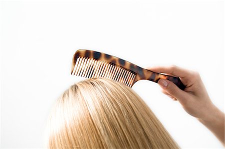 Portrait of a young woman combing her hair, close up, studio Stock Photo - Premium Royalty-Free, Code: 6108-05855800