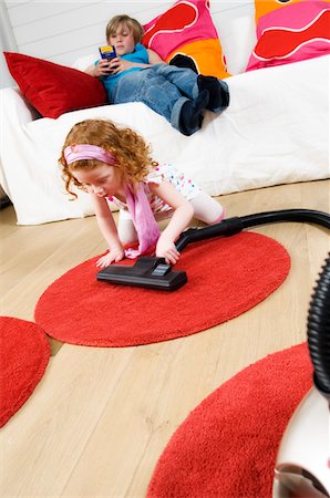 simsearch:6108-05858292,k - 2 children at home, little girl vacuuming, little boy sitting on a sofa Stock Photo - Premium Royalty-Free, Code: 6108-05856065