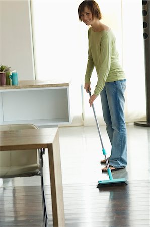 simsearch:6108-05858292,k - Young smiling woman sweeping living-room floor Stock Photo - Premium Royalty-Free, Code: 6108-05856321